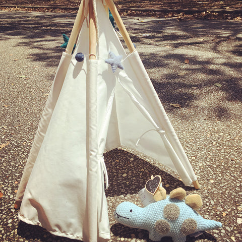 miniature white cotton teepee tent draped with a star and ball garland in ocean colours with a baby dinosaur soft toy inside the teepee